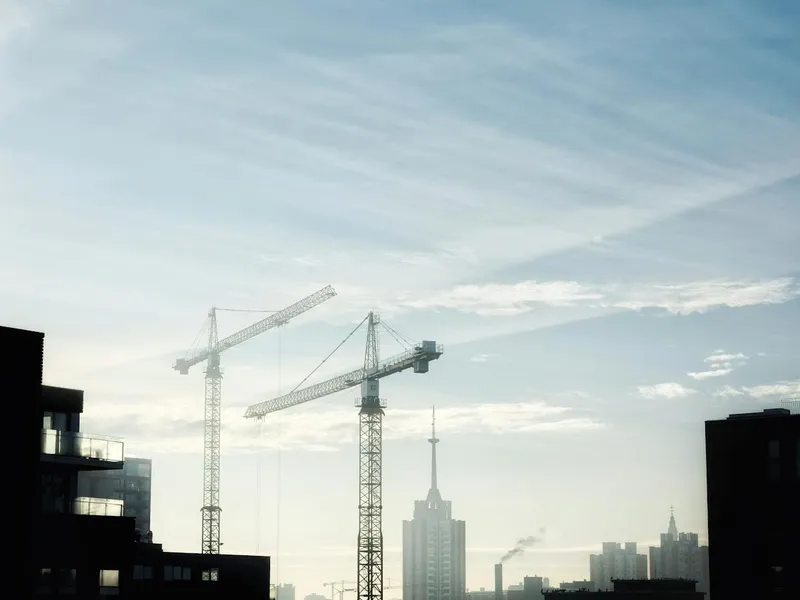 Construction cranes rising over the city skyline